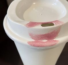 two white vases with pink lipstick on the bottom one has a hole in it