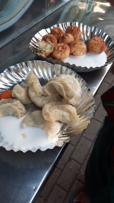 two plates with dumplings and other food items on them