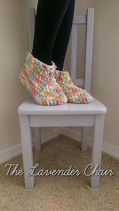 someone is standing on a chair with crocheted slippers