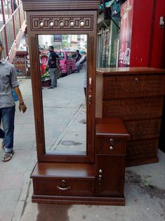 a woman is walking past a mirror on the sidewalk in front of a storefront