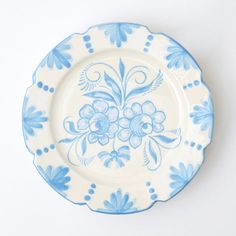 a blue and white plate with flowers painted on the side, sitting against a white background