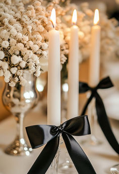 white flowers and candles on a table with black ribbon