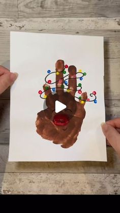 two hands holding up a handprint with christmas lights on it