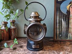 an antique oil lamp sitting on top of a wooden table next to a potted plant