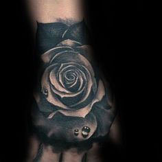 a black and white rose tattoo on the left hand