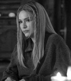 a woman sitting at a table with candles in front of her and looking off to the side