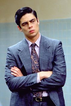 a man in a suit and tie standing with his arms crossed