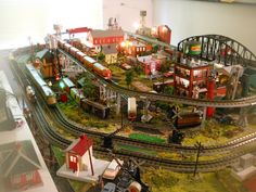 a model train set is shown with buildings and trains on the tracks in front of it