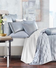 a bed with white sheets and pillows on top of it next to a side table