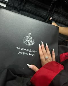 a woman's hand with white nail polish on her nails holding an official document