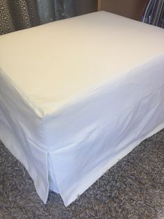 a white bed skirt sitting on top of a carpeted floor