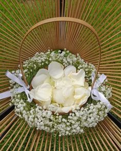 a basket filled with white flowers sitting on top of a wooden table next to grass