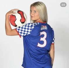 a woman holding a soccer ball in her right hand and posing for a photo with the number three on it