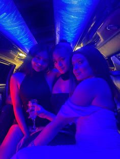 three beautiful women sitting in the back of a limo with blue lights on it's walls