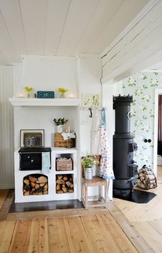 a living room filled with furniture and a fire place in the middle of a wooden floor