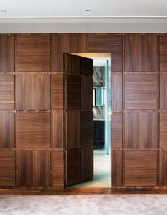 an open wooden door in the middle of a room with carpet on the floor and walls