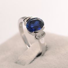 a ring with a blue stone on it sitting on top of a white cloth covered surface