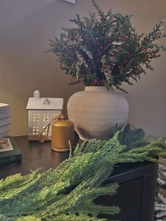 a vase filled with red berries sitting on top of a table next to other items