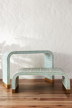 a green bench sitting on top of a wooden floor next to a white wall in a room