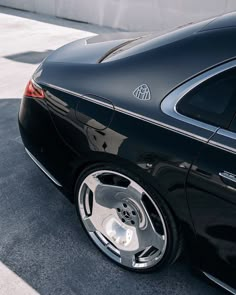 the rear end of a black car with chrome rims and spokes on it