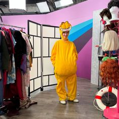 a man in a yellow costume standing next to a rack of clothes