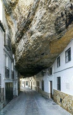 an alley way with buildings and a large rock