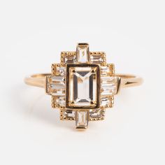 a gold ring with an emerald and baguette cut diamond set in the center