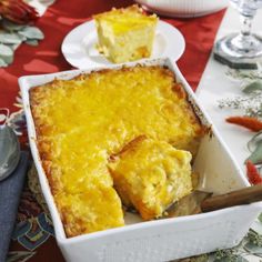 a casserole dish on a table with two plates and silverware next to it