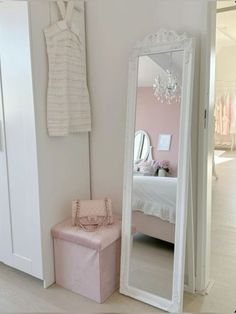 a mirror sitting next to a pink bench in a room with white walls and flooring