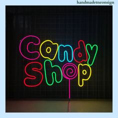 a neon sign that says comedy shop on it's side in front of a black wall