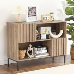 a wooden shelf with books and pictures on it next to a potted plant in a living room