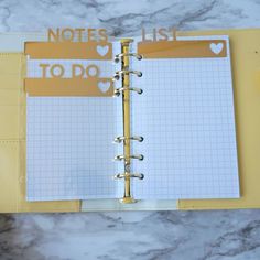 an open planner book with notes to do and heart stickers on the pages, sitting on a marble surface