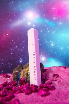 a pink tube sitting on top of a pile of rocks in front of a space filled with stars