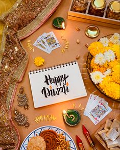 a happy diwali written on a notepad surrounded by food and decor items