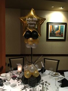 the table is set with black and gold balloons