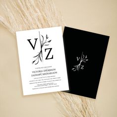 a black and white wedding card with the letter vz on it next to some dry grass