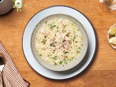 a bowl of soup with chicken and parsley in it on a table next to utensils