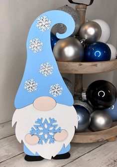 a gnome with snowflakes on his head is standing in front of some ornaments