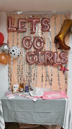 a party table with balloons, confetti and other items on it that say let's go girls