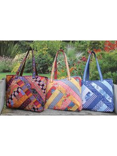 three colorful bags sitting on top of a cement bench