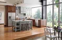 a large kitchen with wooden floors and white cabinets is pictured in this image, there are two stools at the center of the island