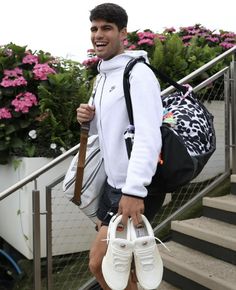 a young man is walking down the stairs with his backpack and shoes in front of him