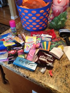 a blue basket filled with candy on top of a counter next to a pink candle