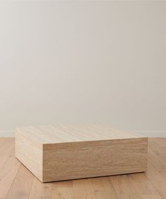 a wooden box sitting on top of a hard wood floor next to a white wall