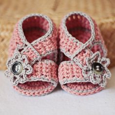 a pair of pink crocheted baby shoes with buttons on the front and bottom