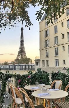 the eiffel tower is seen in the distance from an outdoor dining area with tables and chairs