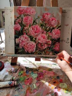 a person is painting flowers on an easel