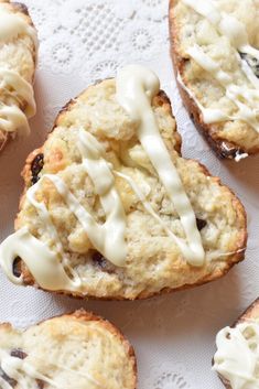 several scones with icing and chocolate chips on a white doily lined table