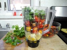 a blender filled with lots of vegetables on top of a wooden counter