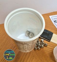 a cup that is sitting on a table next to some balls and a pair of scissors